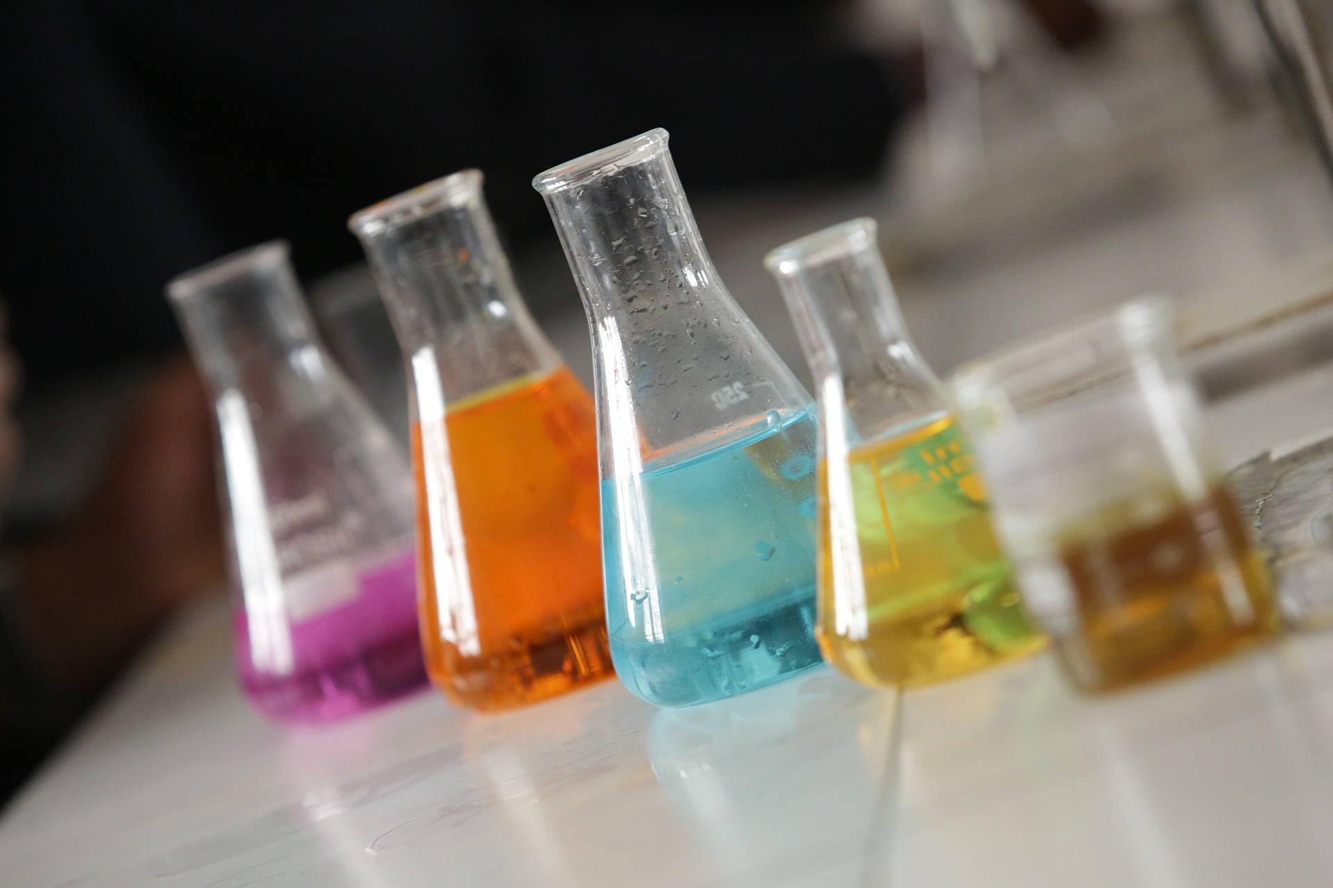 brightly coloured solutions in conical flasks